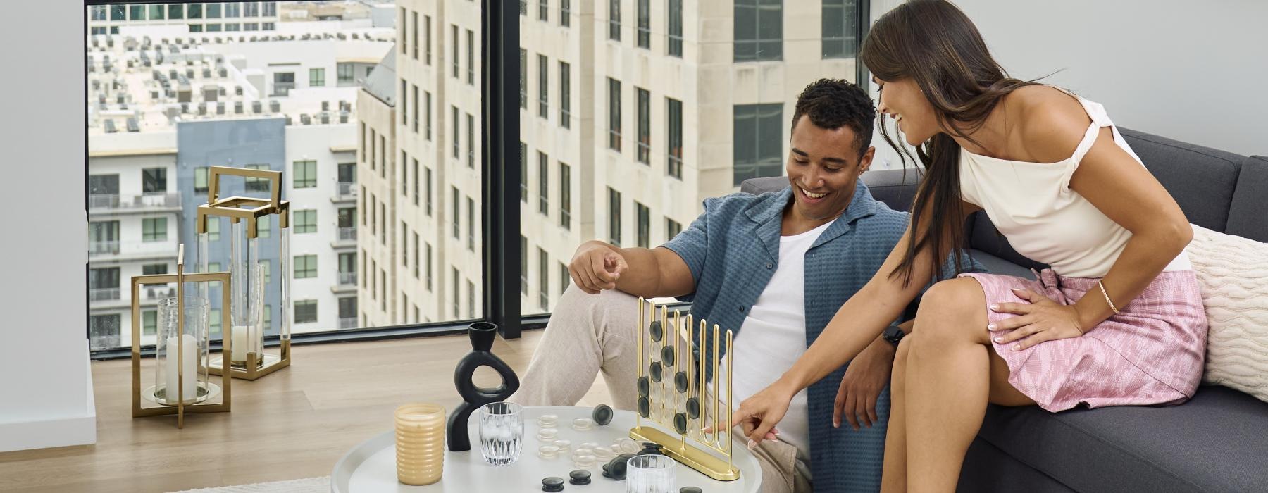 a man and woman sitting on a couch in front of a window